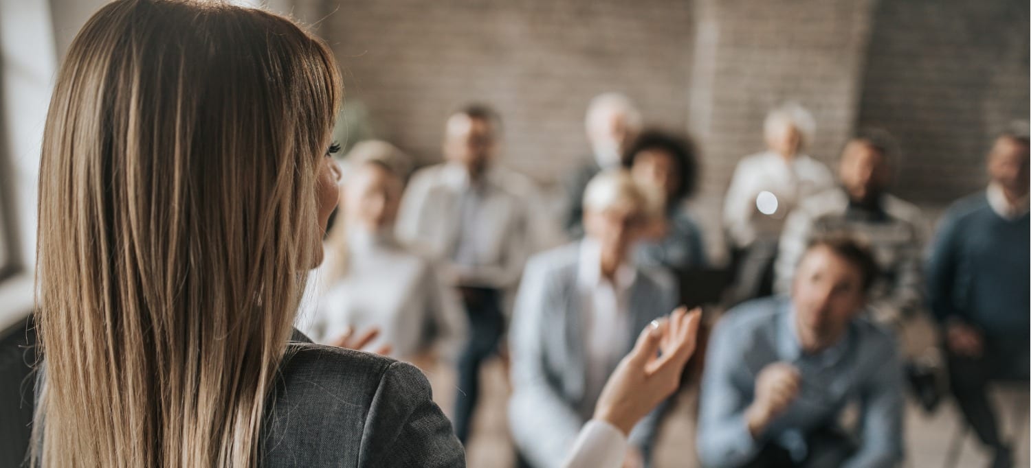 female manager talking to large group of her colleagues on a business conference