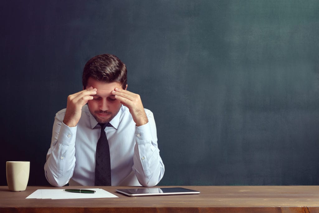 Caucasian casual businessman is working on his desk with his hands on his head stressed.