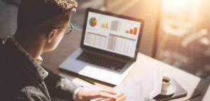 Young finance market analyst at desk with laptop