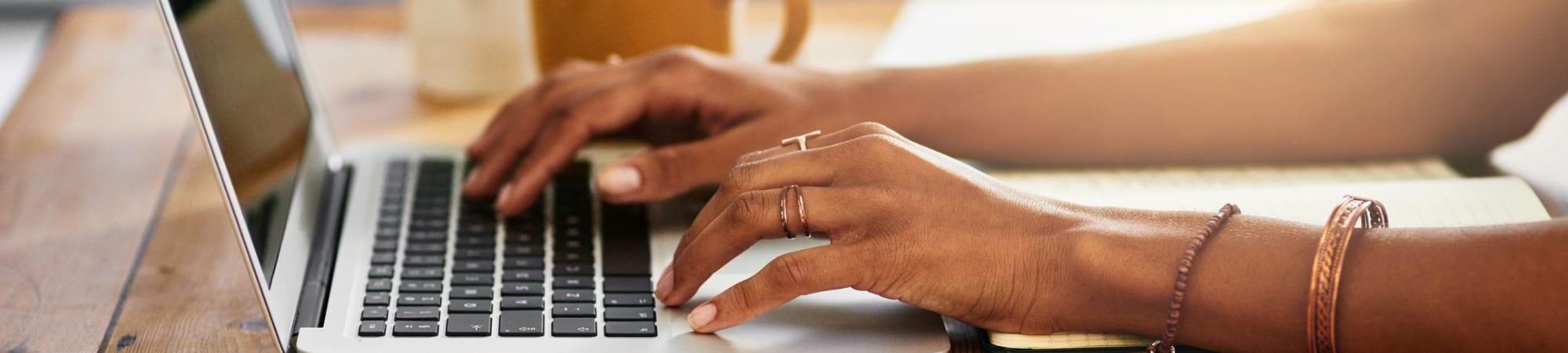 Women's hands typing on a laptop keyboard.