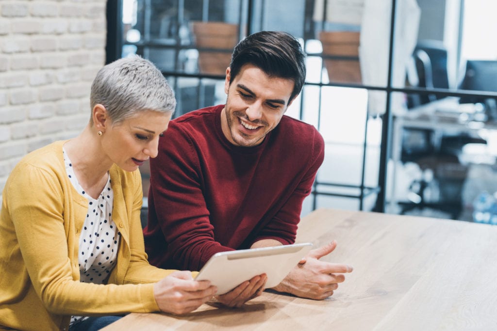 Coworkers discussing idea on digital tablet