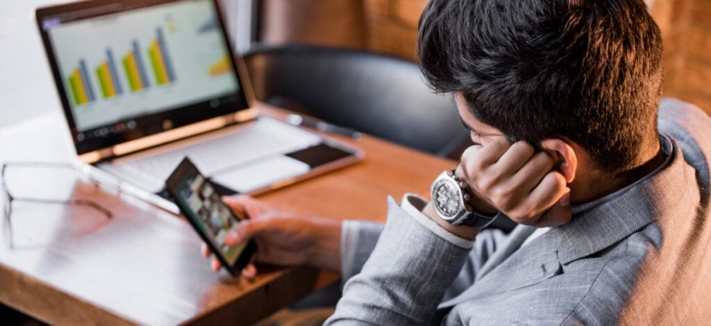 Man sat on phone whilst working in front of his laptop