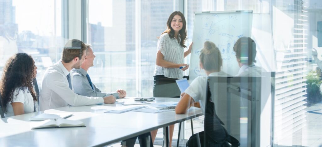 women giving a presentation to her team on a whiteboard