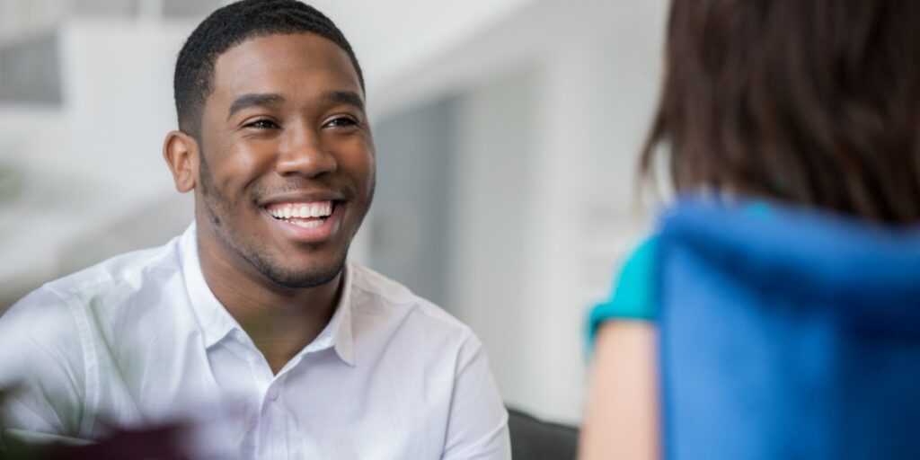 young man smiling at female sitting across from him.