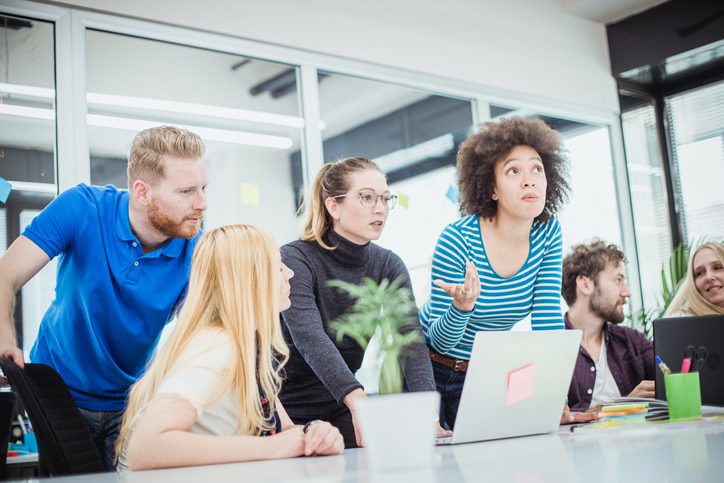 Employees surrounding a laptop screen discussing something