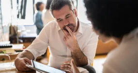 Male and female co worker looking at a tablet screen discussing something