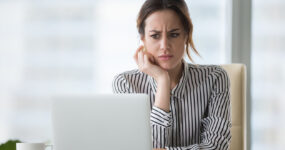 Confused businesswoman annoyed by online problem looking at laptop