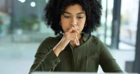 Shot of a young businesswoman looking uncertain while using a laptop in a modern office