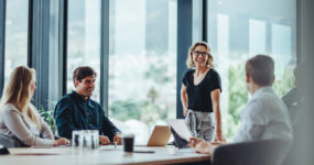 Office colleagues having casual discussion during meeting in conference room. Group of men and women sitting in conference room and smiling.