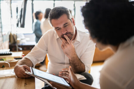 Mature man looking at a digital tablet that a colleague is showing at work