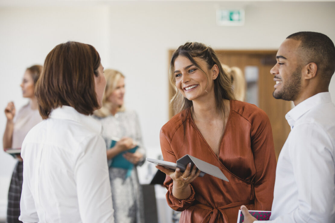 Two females and a male speaking to each other at a networking event