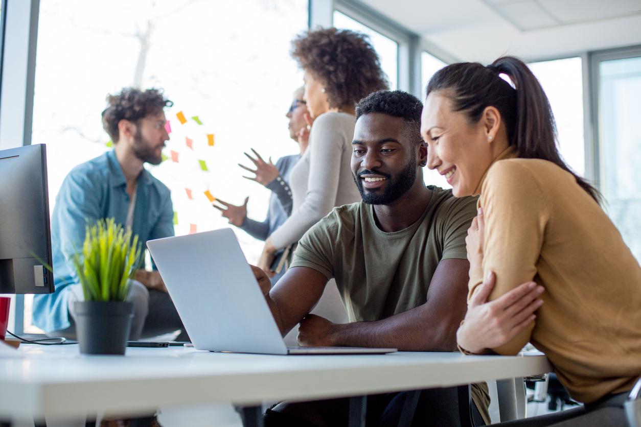 Two employees huddled around computer screen speaking through work