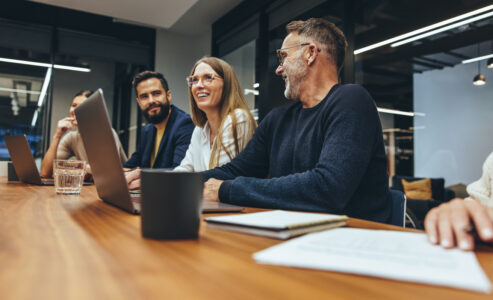 Three employees sat at a meeting table having a discussion