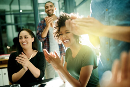 Shot of a team of creative businesspeople applauding an achievement while working late in the boardroom