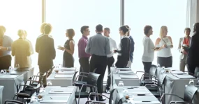 Large group of employees having individual conversations with each other in a large room