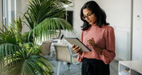 Female employee stood alone using a tablet in a meeting room