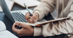 Cropped image of hands writing in a notebook