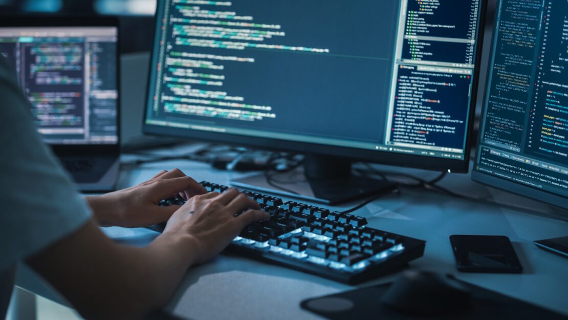 Cropped photo of a mans hands typing code