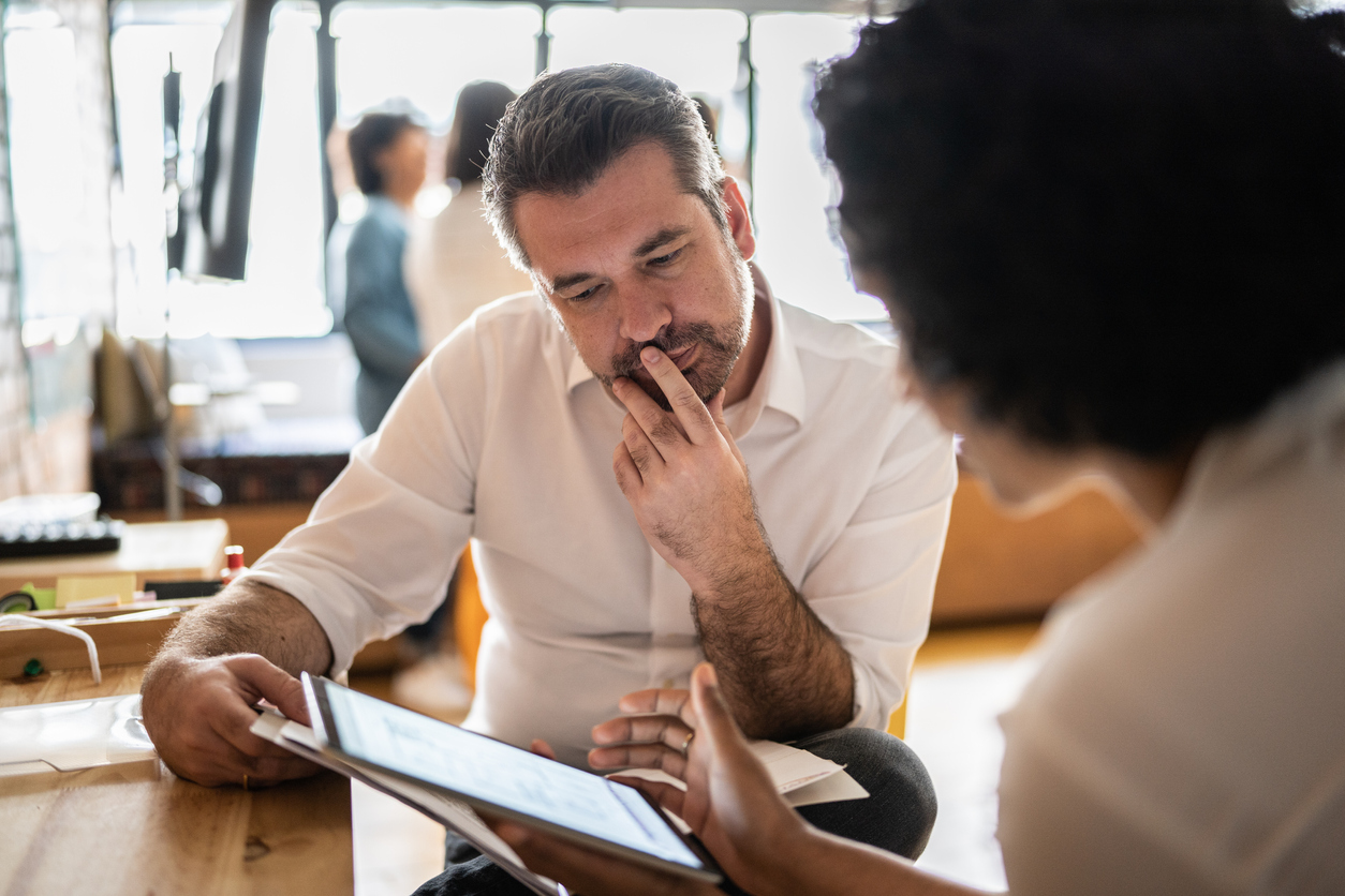 Male and female employee staring intensely at a tablet