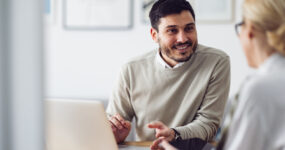 Two employees speaking to each other over a laptop