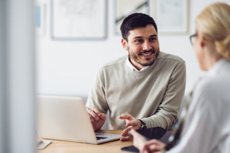 Two employees speaking to each other over a laptop 