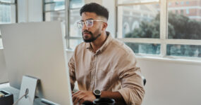 Man in light brown top working on a computer monitor concentrating