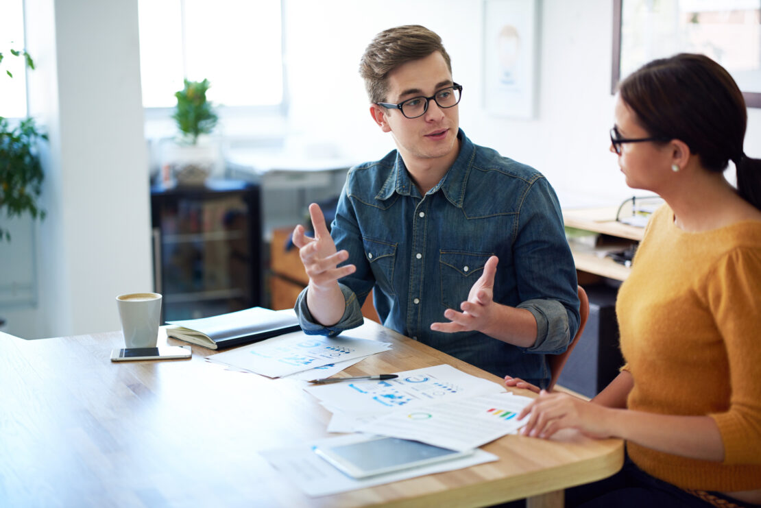 Two employees having a casual meeting at a wooden table