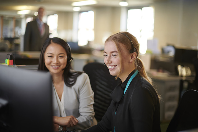 Two females laughing and smiling together whilst collaborating