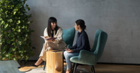 Two females sat on comfy chairs discussing with each other