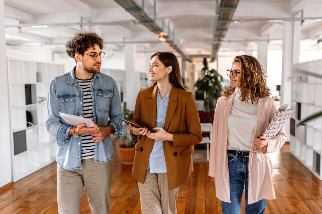 Three employees walking through an open office space