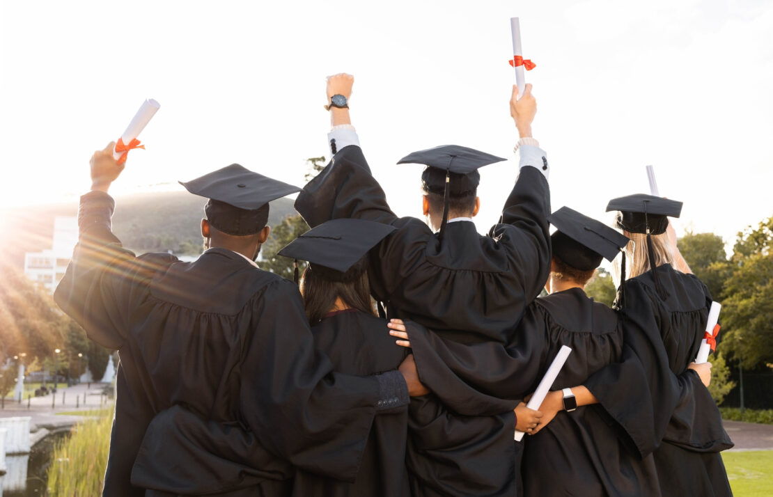 Backshot of students in cap and gown celebrating graduating