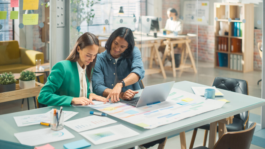 Two females sat together working on printed out paper reports