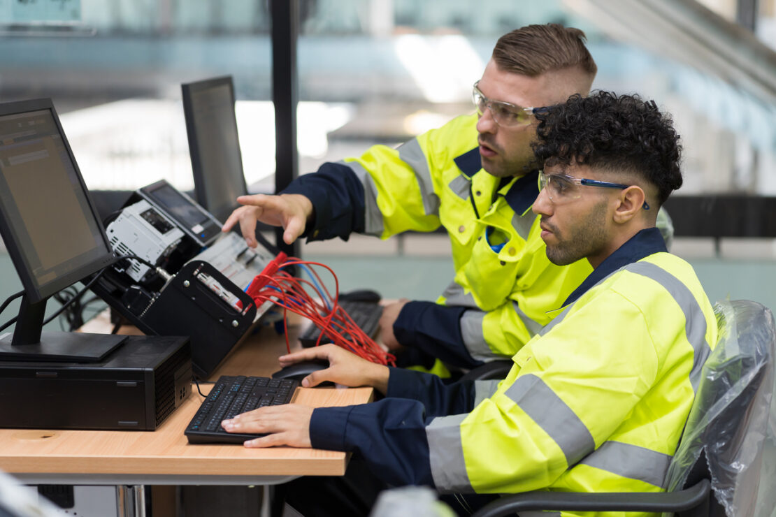 Two males in hi vis jackets fixing electronics