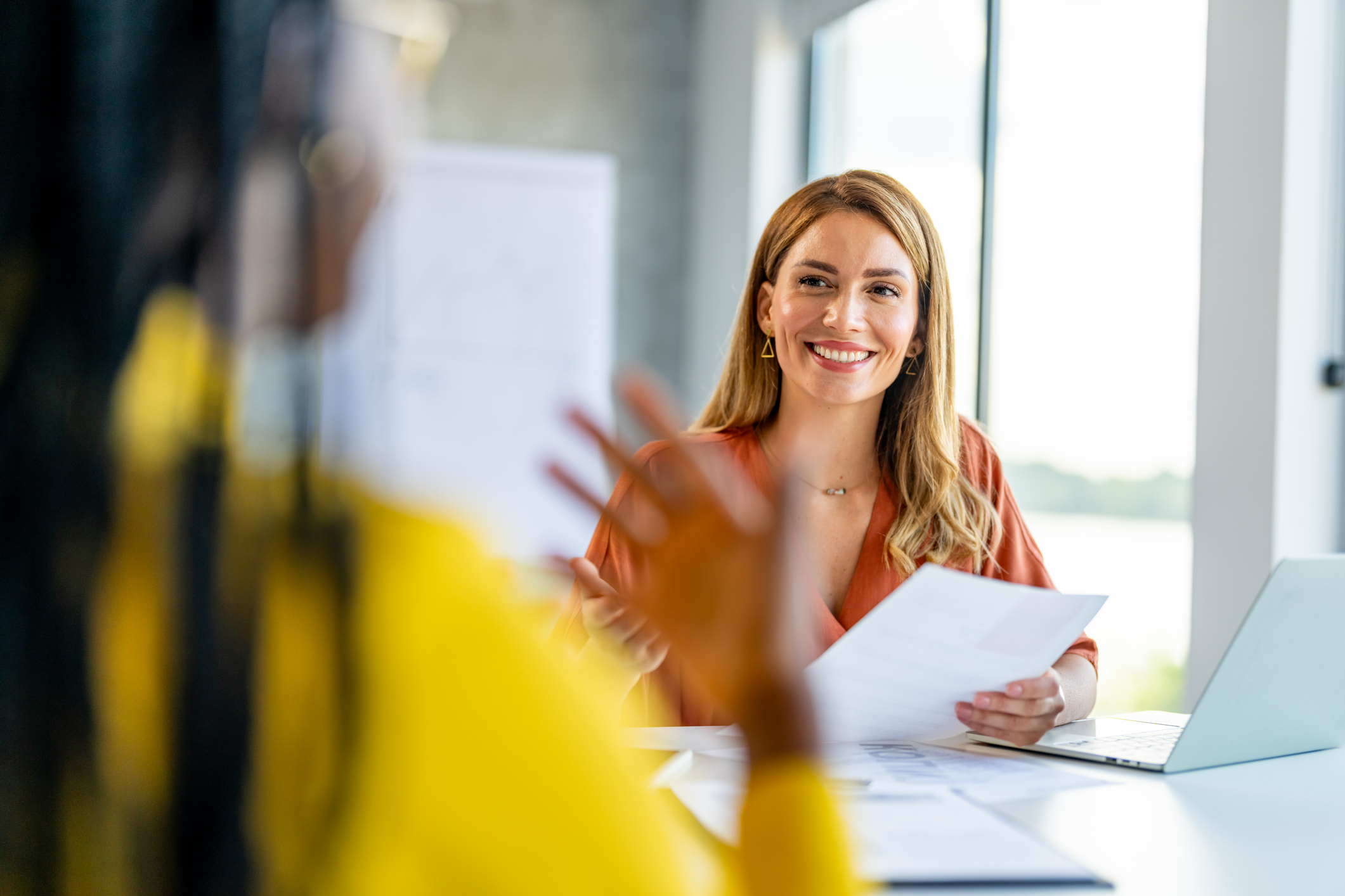 two female professionals in conversation sat at a desk